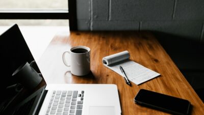 MacBook Pro, white ceramic mug,and black smartphone on table