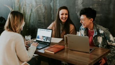 three people sitting in front of table laughing together