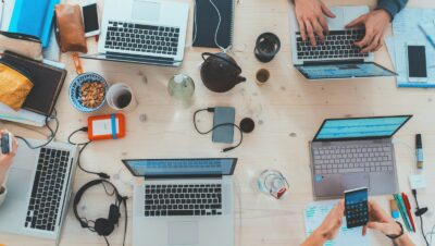 people sitting down near table with assorted laptop computers