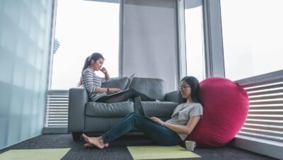 two women sitting on sofa and floor inside gray painted room