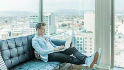 man sitting on sofa while using laptop