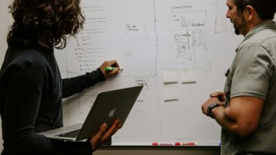 man wearing gray polo shirt beside dry-erase board