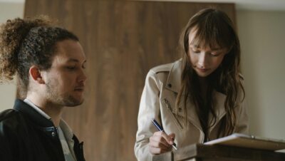 A Woman Signing a Document Beside a Man