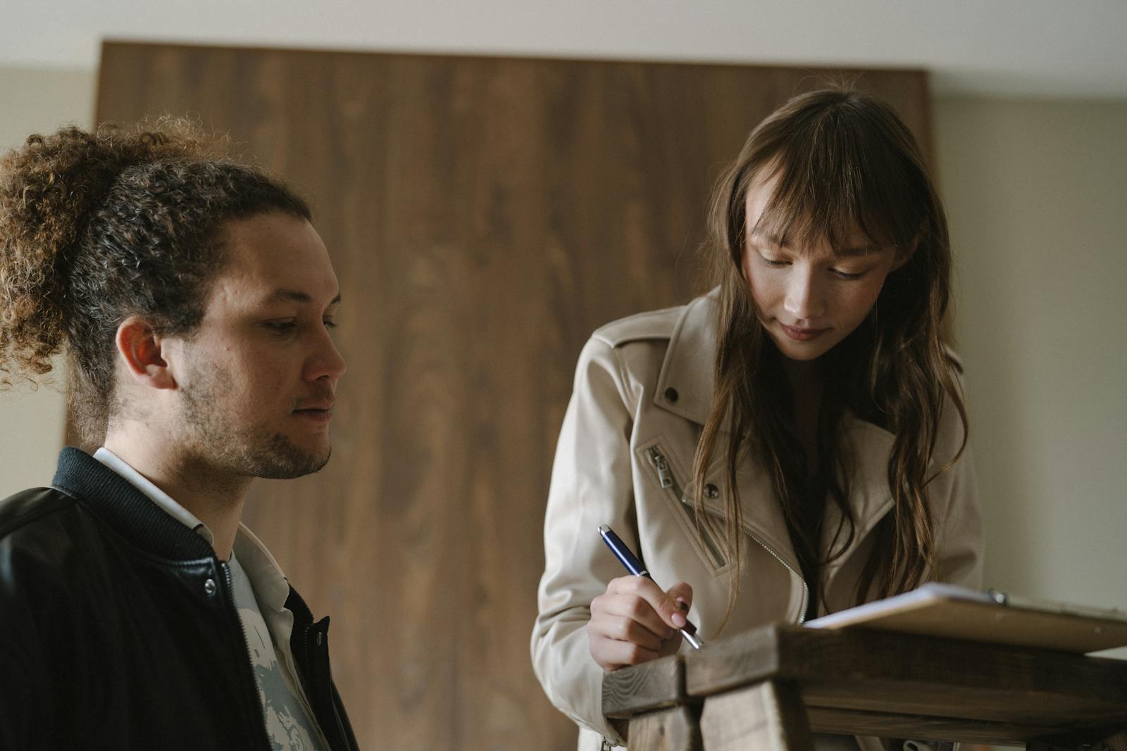 A Woman Signing a Document Beside a Man