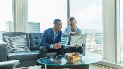 two men in suit sitting on sofa