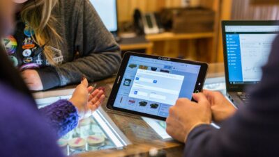 two people sitting at a table looking at a tablet