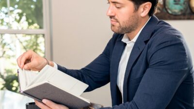 man in blue suit reading book