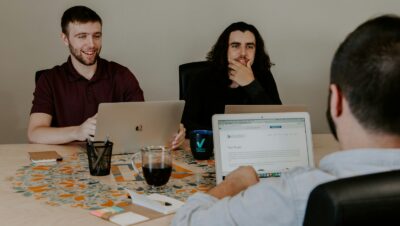 three person sitting in-front of table with laptop computers