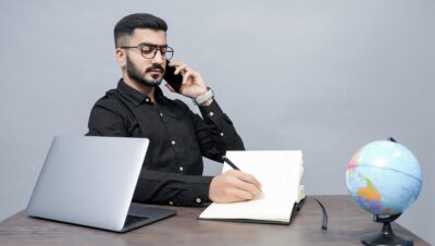 a man holding a pen and a book and a laptop